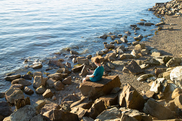 Teenage boy sitting on a large while playing on his phone at Boulevard Park