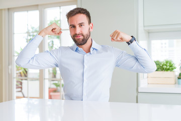 Fototapeta premium Handsome business man showing arms muscles smiling proud. Fitness concept.