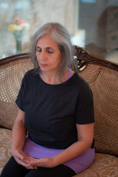 Senior Indian woman with grey hair and glowing skin, meditating in the morning. 