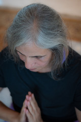 Senior Indian woman with grey hair and glowing skin, meditating in the morning. 