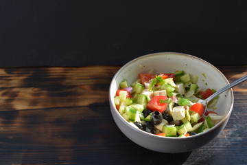 a bowl of fresh salad chopped into small blocks on a wooden background
