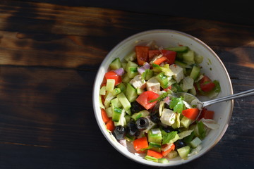 a bowl of fresh salad chopped into small blocks on a wooden background