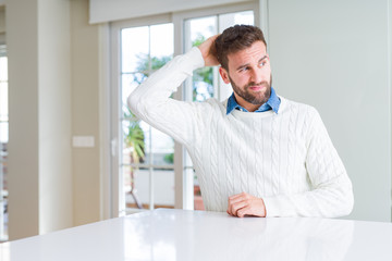 Fototapeta premium Handsome man wearing casual sweater confuse and wonder about question. Uncertain with doubt, thinking with hand on head. Pensive concept.
