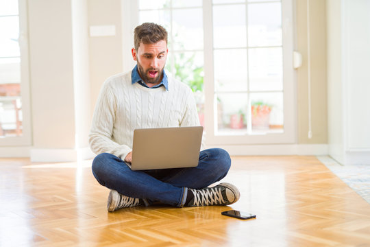 Handsome man wearing working using computer laptop scared in shock with a surprise face, afraid and excited with fear expression