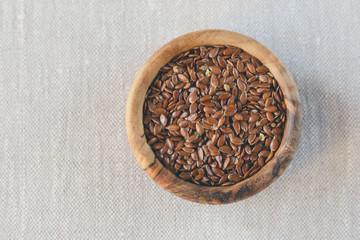 Flax seeds Linum usitatissimum are useful in a bowl of olive wood on flax. Product for beauty and health. Proper nutrition.