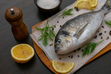 Dorado fish on a cutting board with salt and spices lemon slices. Food photo.