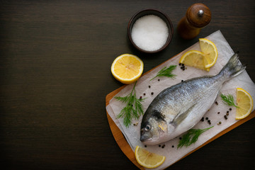 Dorado fish on a cutting board with salt and spices lemon slices. Food photo.