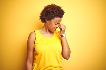 Beauitul african american woman wearing summer t-shirt over isolated yellow background tired rubbing nose and eyes feeling fatigue and headache. Stress and frustration concept.