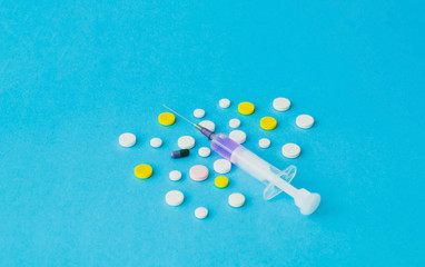 Pills and medical syringe on blue background. Drug prescription for treatment medication