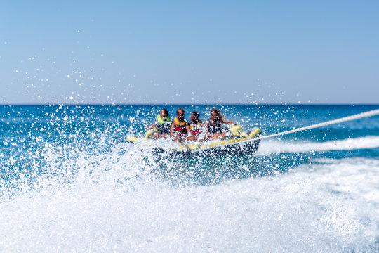 Group of happy  friends sitting on a boat with waves