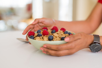 Close up of young woman eating healthy cereals and berries for breakfast