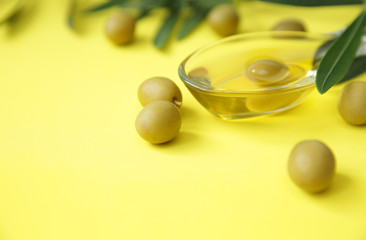 Close-up olive oil in a glass in the form of olives and olive branch with green olives on a yellow background. Ingredients for the kitchen. Healthy eating Mediterranean diet. With copy space 