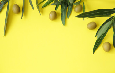 Flat lay. Organic green olives with olive leaves on a yellow background. Healthy food....