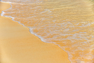 Fototapeta na wymiar Tropical beach​ blue​ ocean wave and​ bubble. Soft beautiful sea water and yellow sand background.