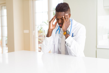 African american doctor man at the clinic with hand on head for pain in head because stress....