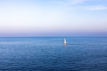 Fototapeta premium Lonely sailboat sailing at sunset on the Mediterranean