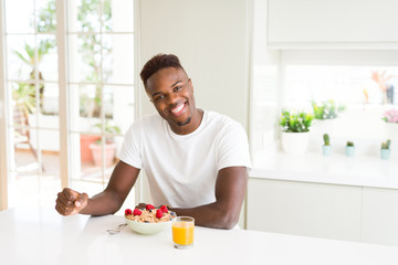 Handsome african american man eating heatlhy cereals and berries as breakfast