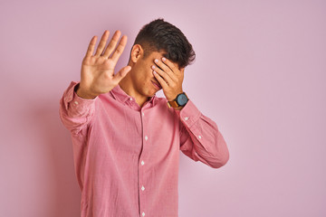 Young indian man wearing elegant shirt standing over isolated pink background covering eyes with hands and doing stop gesture with sad and fear expression. Embarrassed and negative concept.