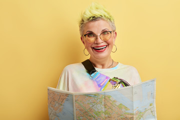 Happy funny positive woman holding a map - isolated over a yellow background. close up portrait. happiness concept