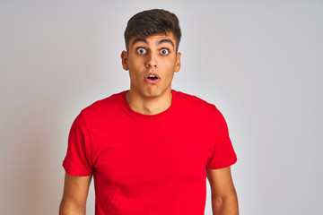 Young indian man wearing red t-shirt standing over isolated white background afraid and shocked with surprise expression, fear and excited face.