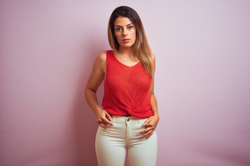 Young beautiful hispanic woman standing wearing orange t-shirt