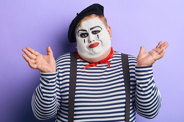 unhappy mime showing shrug gesture isolated on blue, body language, isolated blue background. indifference, apathy