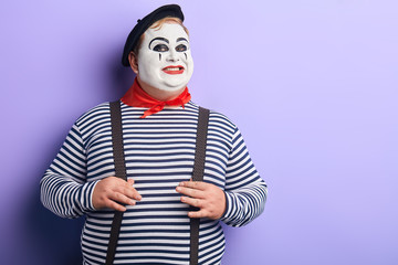 happy mime artist with cunning smile stetching , touching his suspenders looking at the camera . comedy sketch.copy space. isolated blue background.