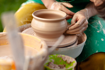 Hand craft making pottery on wheel. Female hands mold ceramic plate from clay (pot).