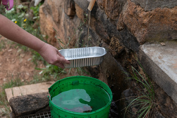 mountain landscape with water tap and green bucket