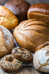 Assortment of fresh baked bread and buns on wooden table background