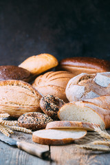 Assortment of fresh baked bread and buns on wooden table background