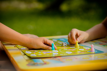 Obraz premium Board game and kids leisure concept. Kids are playing. people holding figures in hand. yellow, blue, green and red wood chips in children play.concept of board games. Dice, chips and cards. Party