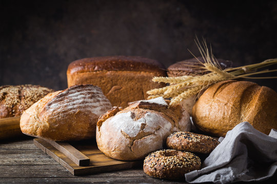 Assortment of fresh baked bread and buns on wooden table background