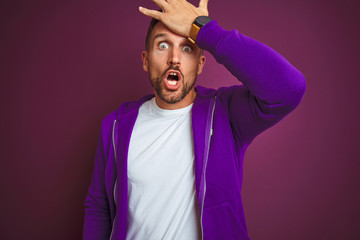 Young fitness man wearing casual sports sweatshirt over purple isolated background surprised with...