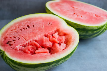 Two half ripe watermelon on a gray background.