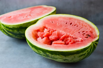 Two half ripe watermelon on a gray background.