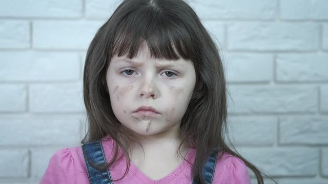 Child abuse. Sad dirty child. Portrait of a dirty resentful little girl.