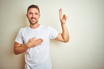 Young handsome man wearing casual white t-shirt over isolated background smiling swearing with hand...