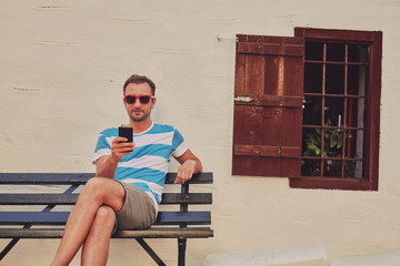 Attractive man using cellphone while sitting on the bench.