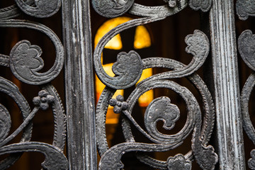 Inside of a mausoleum with a cross seen inside through a metal ornate gate
