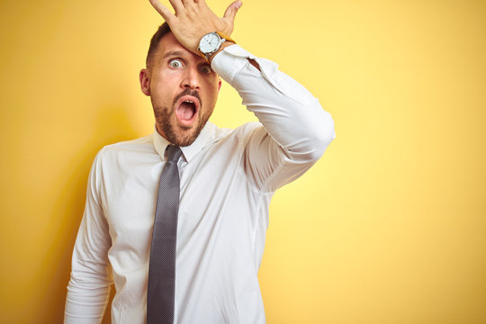 Young handsome business man wearing elegant white shirt over yellow isolated background surprised with hand on head for mistake, remember error. Forgot, bad memory concept.