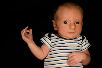 A 3 Week Old Baby Poses on a Black Background. Perfect for Memes with Copy Space.