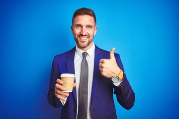 Young handsome business man drinking a coffee on a paper cup over blue isolated background happy...
