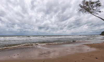 Storming sea with a thundercloud above,  beautiful rugged coastline with waves crashing against the...