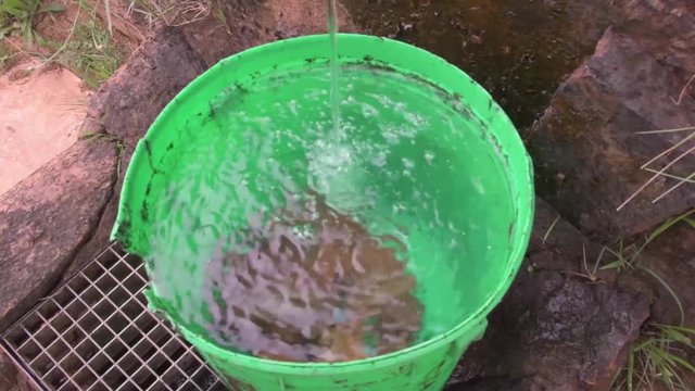 mountain landscape with water tap and green bucket