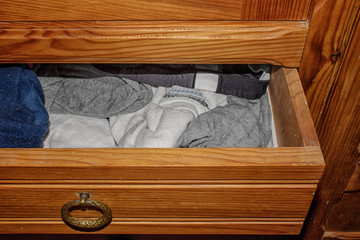 Fototapeta na wymiar Open retractable drawer of an old wooden cabinet with clothes