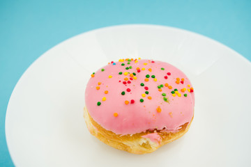 Pink round donut on white plate on blue background