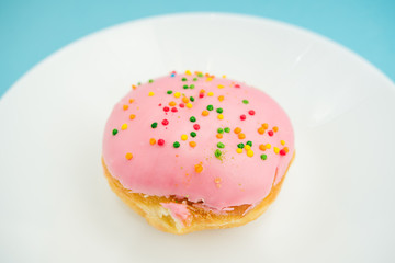 Pink round donut on white plate on blue background