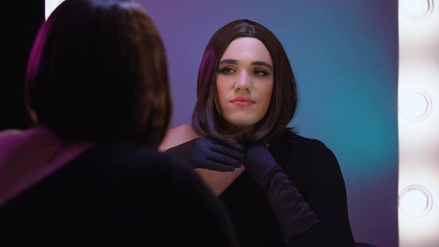 Travesty diva admiring appearance in mirror, trans women beauty and femininity