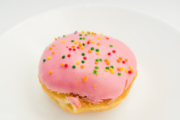 Pink round donut on white plate on white background